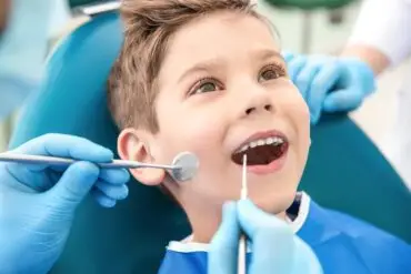 dentist using a dental mirror and explorer checking on a patient's mouth