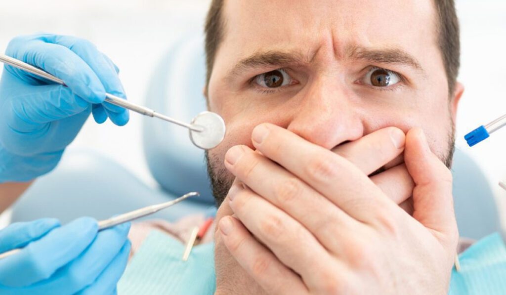 man holding covering his mouth in dentist office