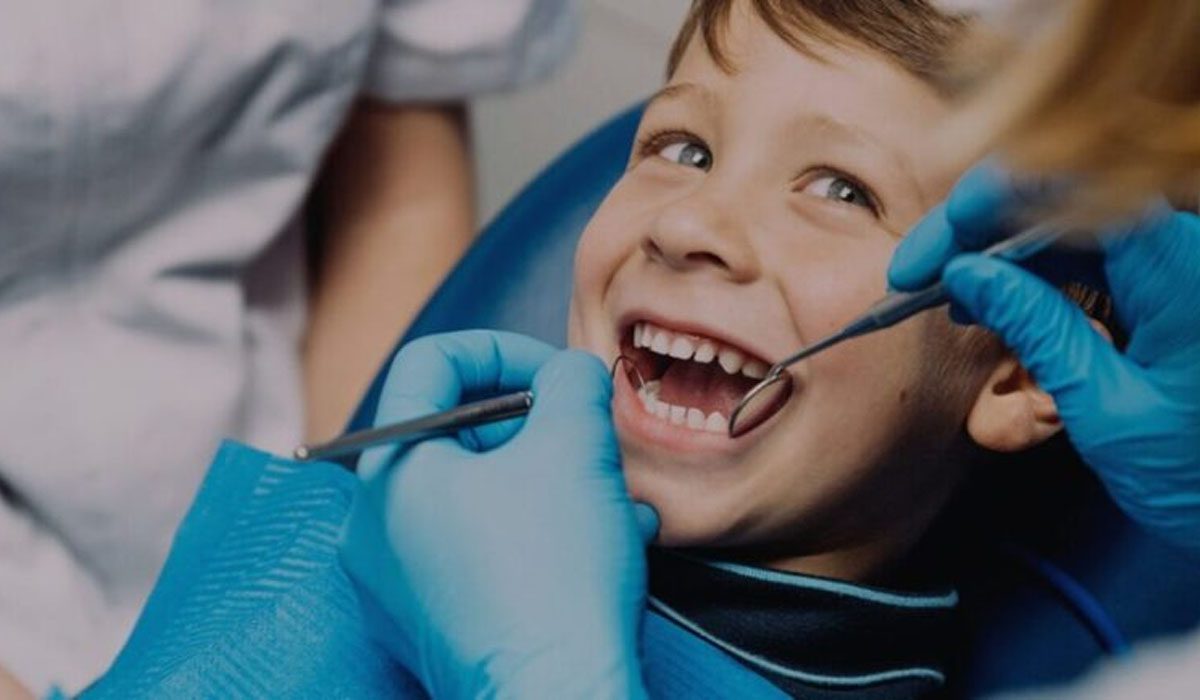 child smiling at dentist while teeth is getting looked at