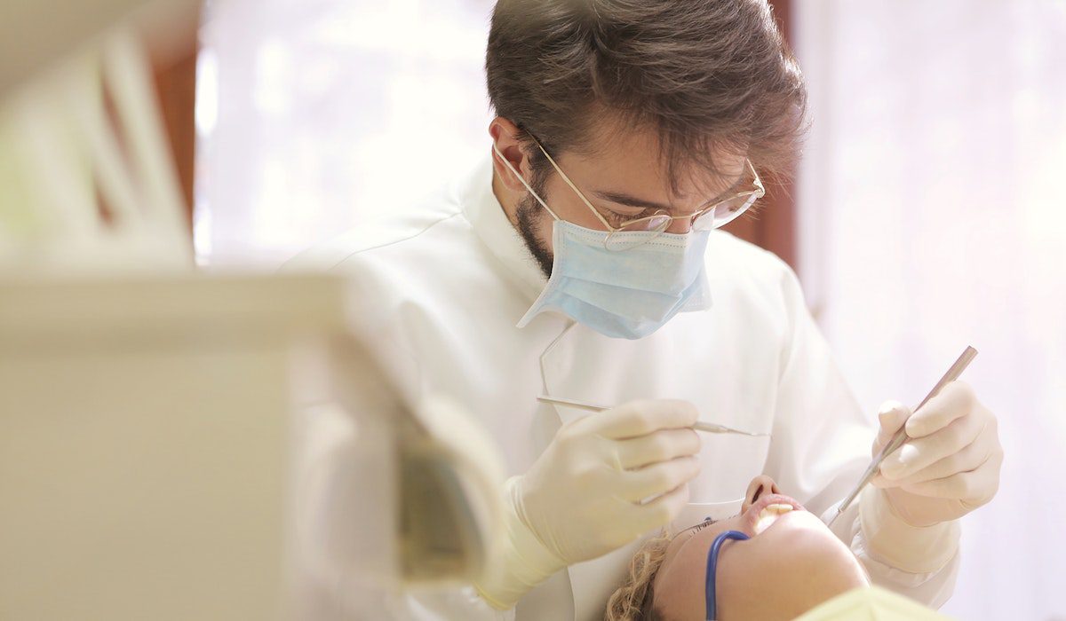 a male dentist checking up a patient;s mouth