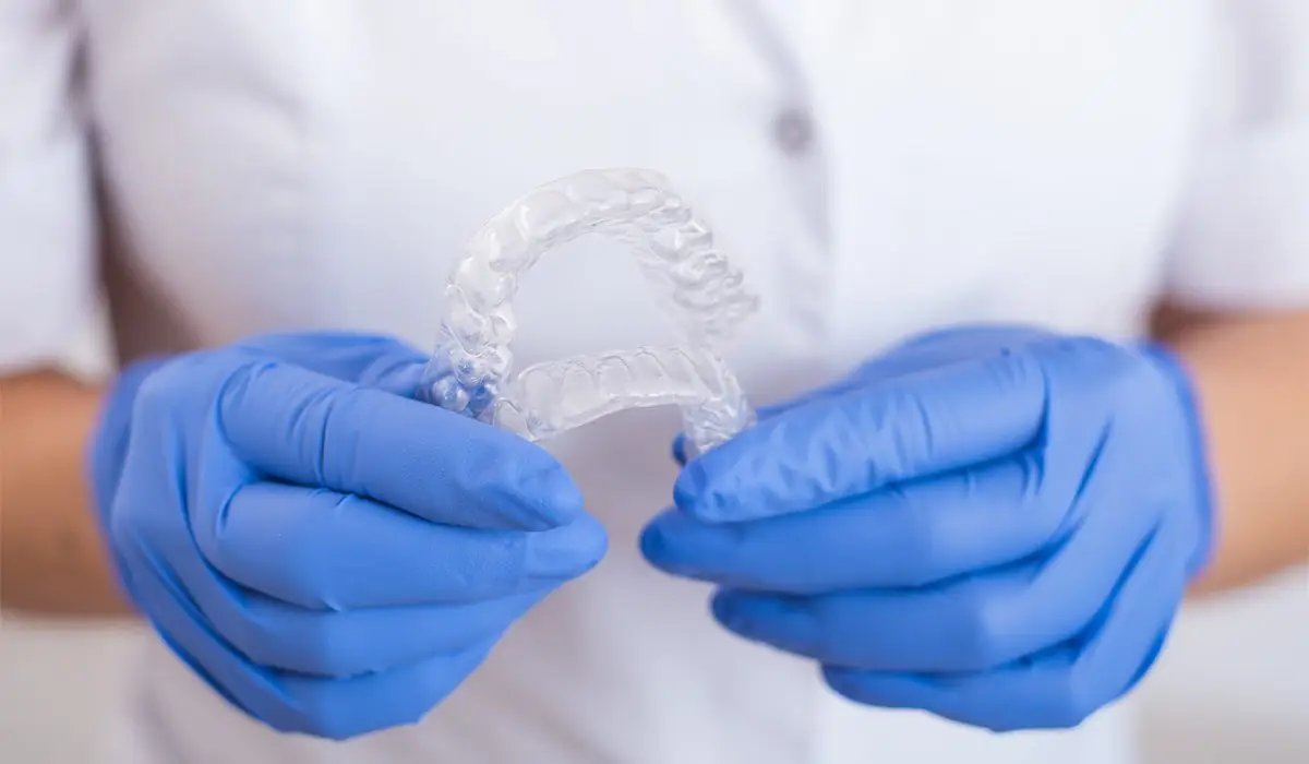 The orthodontist holds the removable transparent retainers.