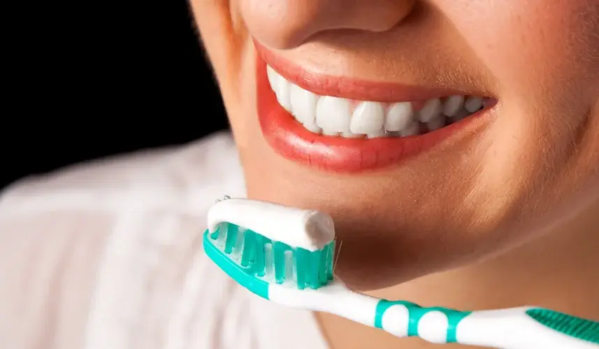 a woman with a healthy teeth holding a toothbrush practicing good oral hygiene