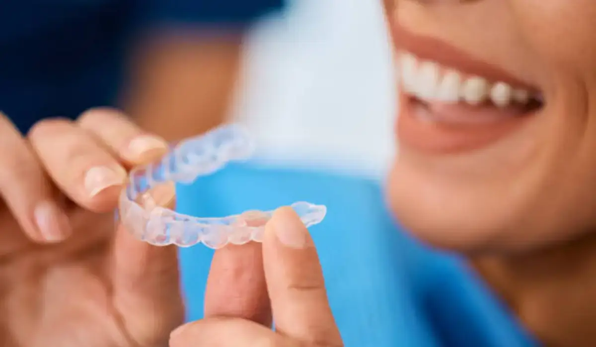 Woman holding Invisalign aligner to manage Invisalign discomfort effectively.