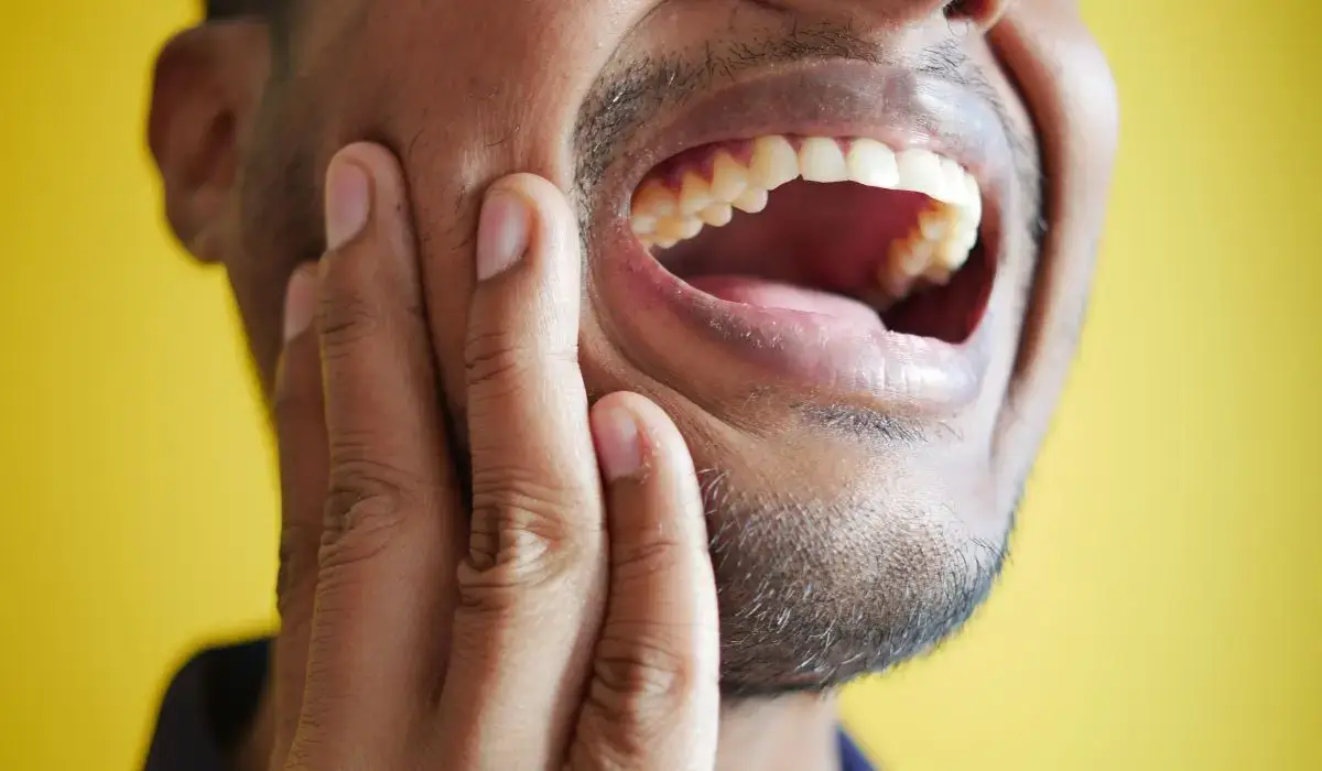 Man clutching jaw in pain, showing signs of dental emergency with possible lockjaw or infection symptoms.