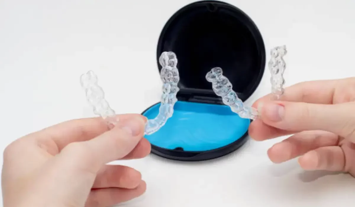 Hands holding Invisalign aligners with a storage case, emphasizing proper care and maintenance.