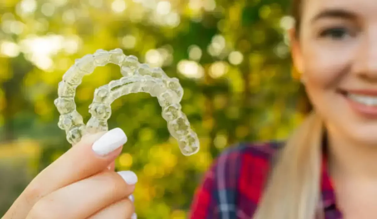 Person holding Invisalign aligners outdoors in autumn, highlighting common Invisalign issues and seasonal care tips.
